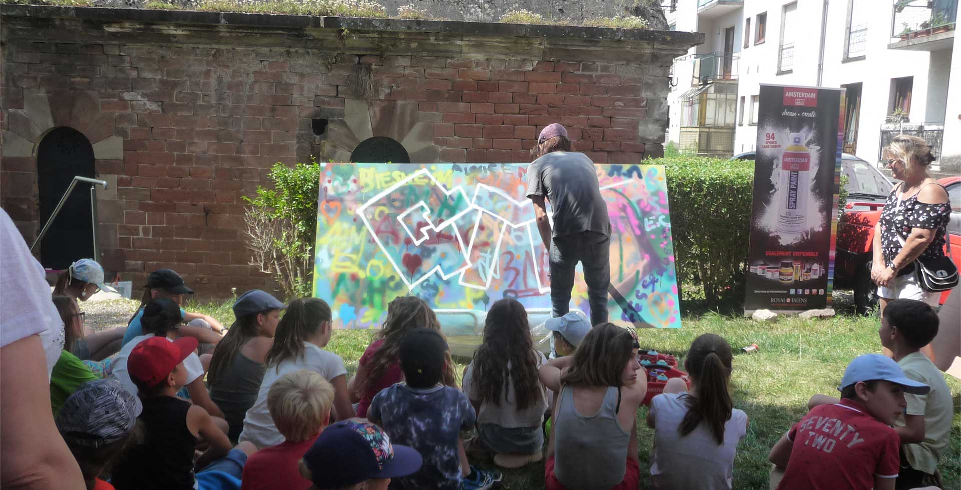 Homme qui peint en plein air devant des enfants