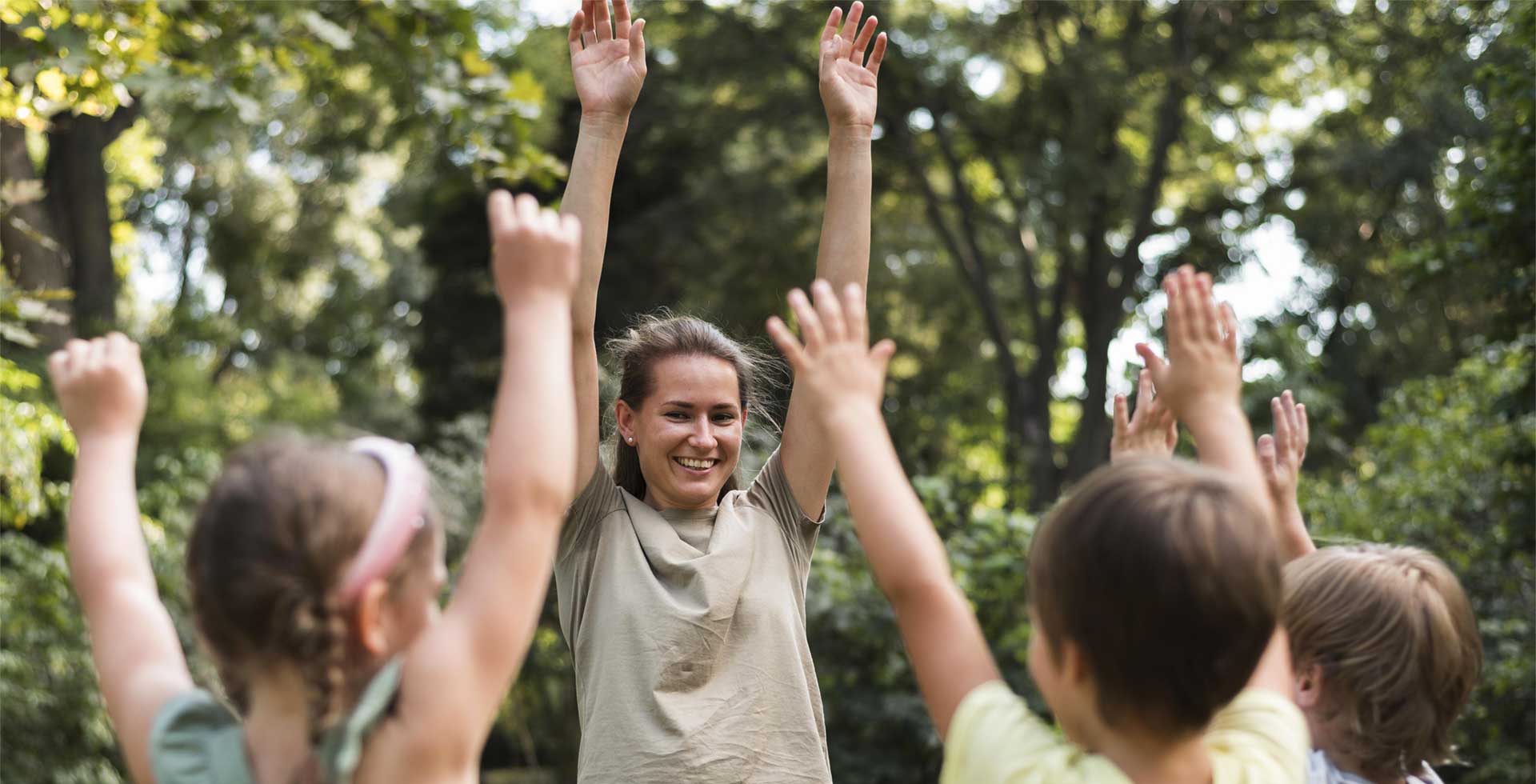 Animatrice qui joue avec des enfants les bras en l'air