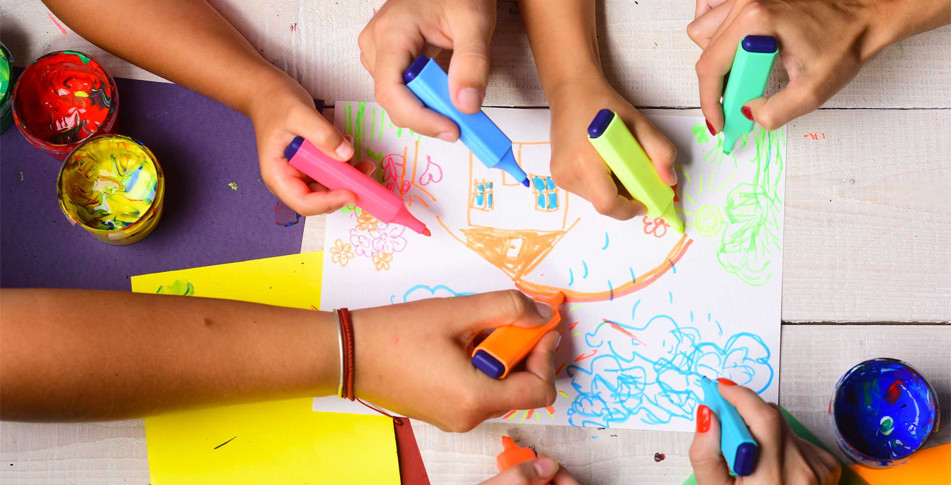 Plusieurs mains d'enfants qui dessinent ensemble sur une feuille