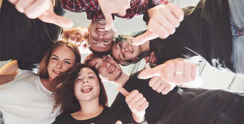 Jeunes souriant en cercle regardant vers le bas avec le pousse levé