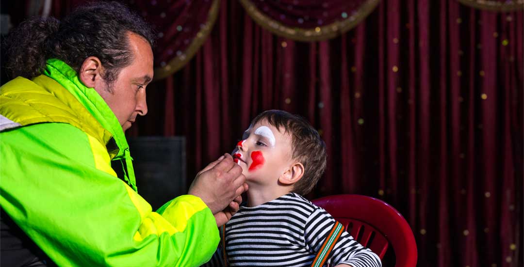 Enfant qui se fait maquiller en clown par un monsieur