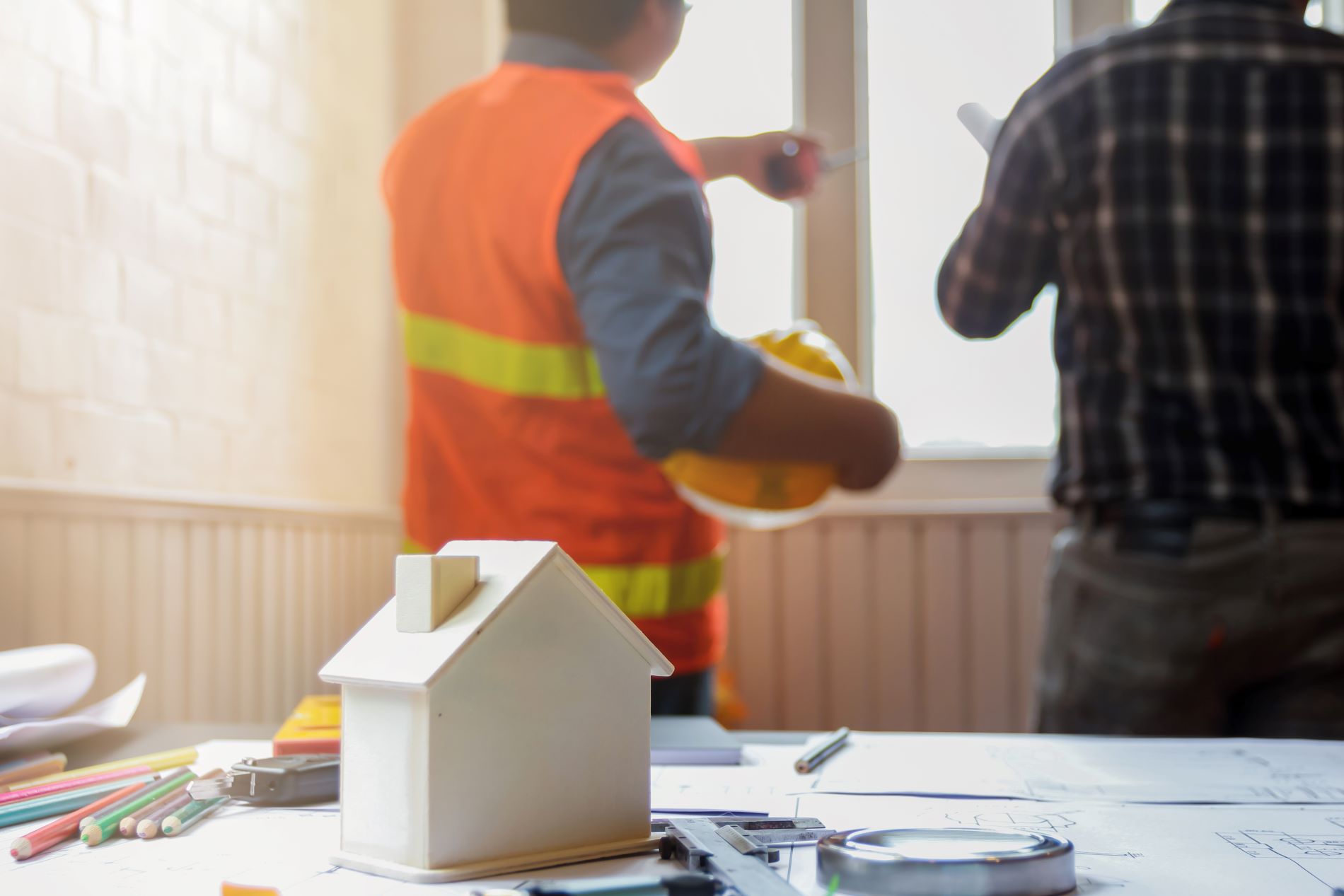 2 ingénieurs vue de dos qui regardent par une fenêtre en tenue de chantier