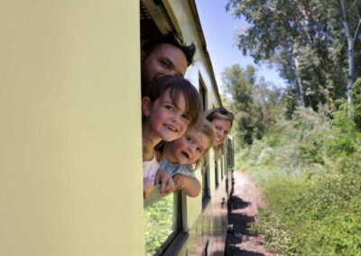 Famille 4 personnes sortant la tes têtes de la fenêtre, les cheveux au vent, et le train roulant.