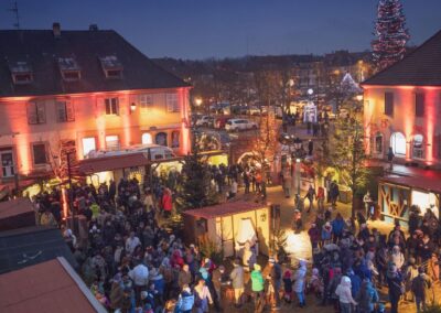 Marché de noël nocturne, avec place bondée, vue en hauteur depuis bâtiment