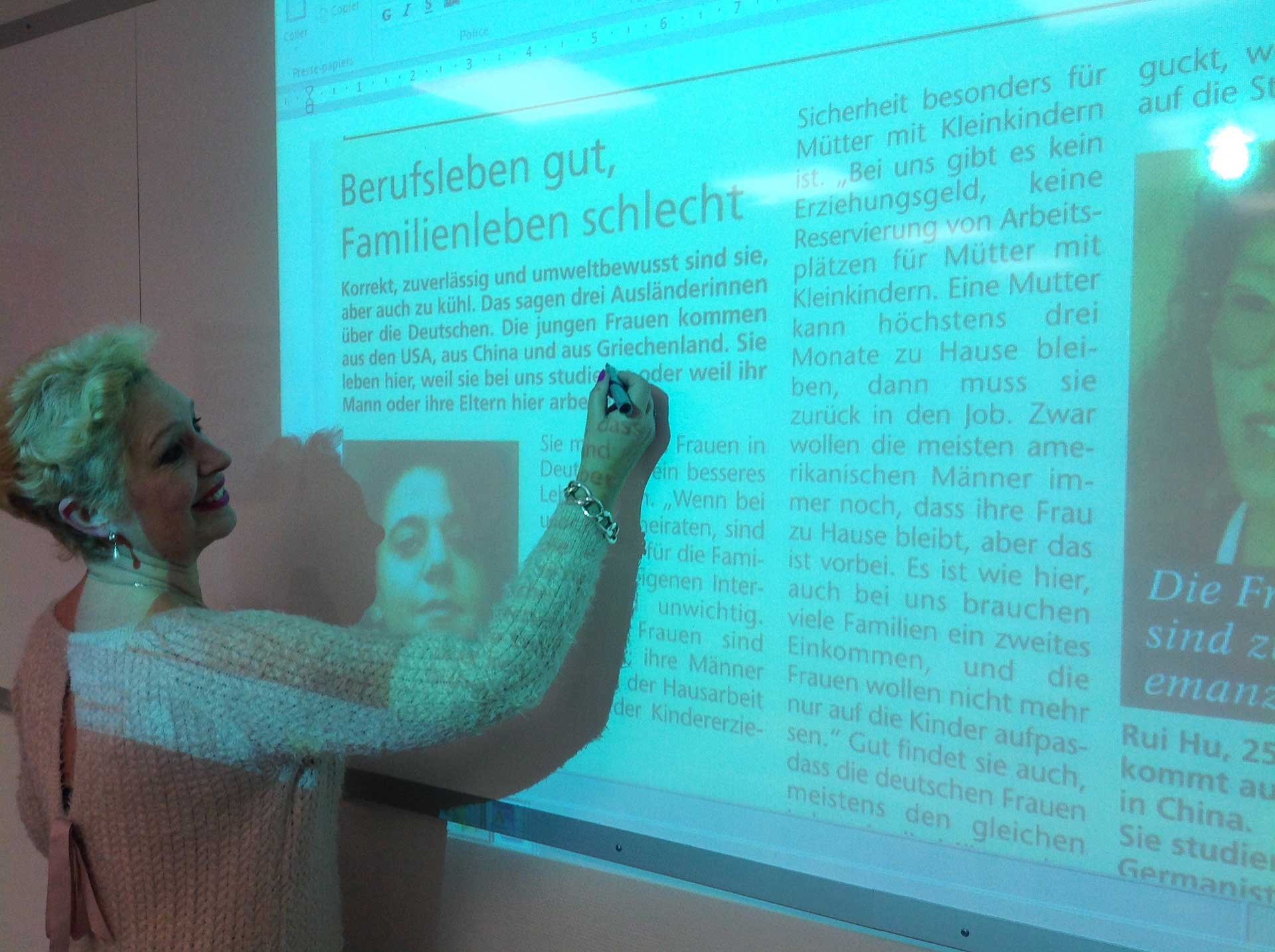 Femme devant tableau blanc qui souligne texte en allemand