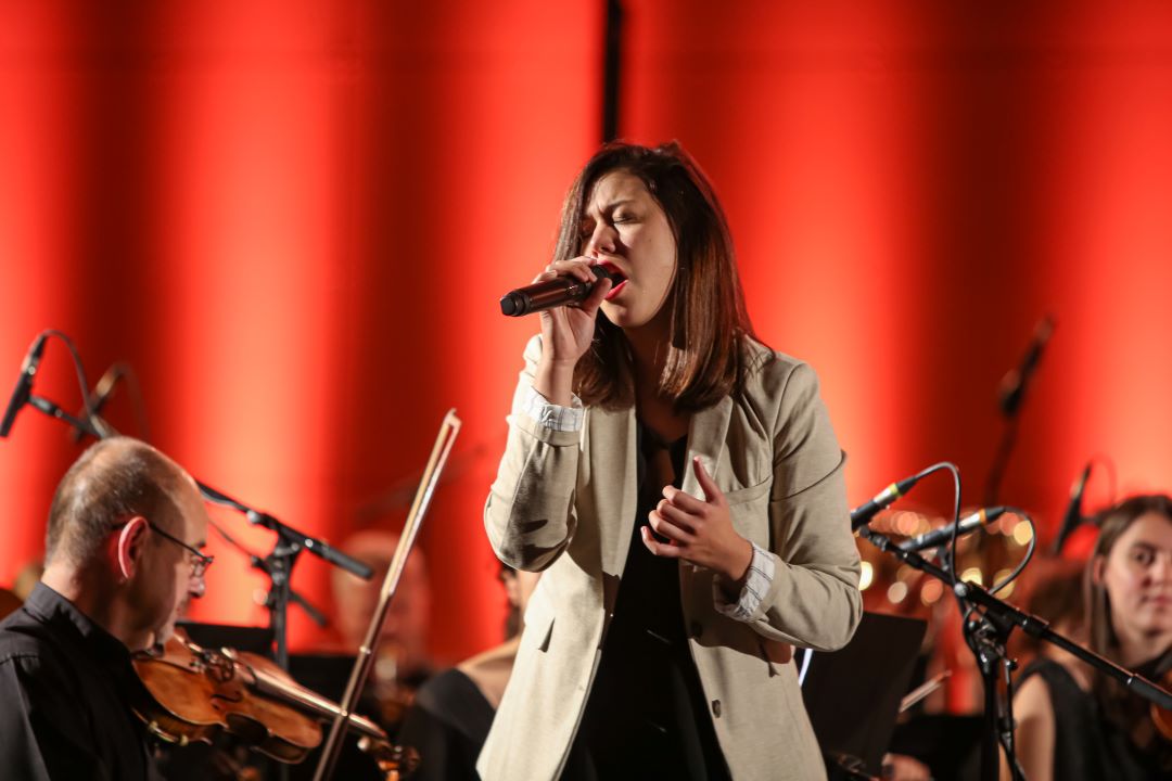 Photo artiste féminine entrain de chanter micro en main, les yeux fermés