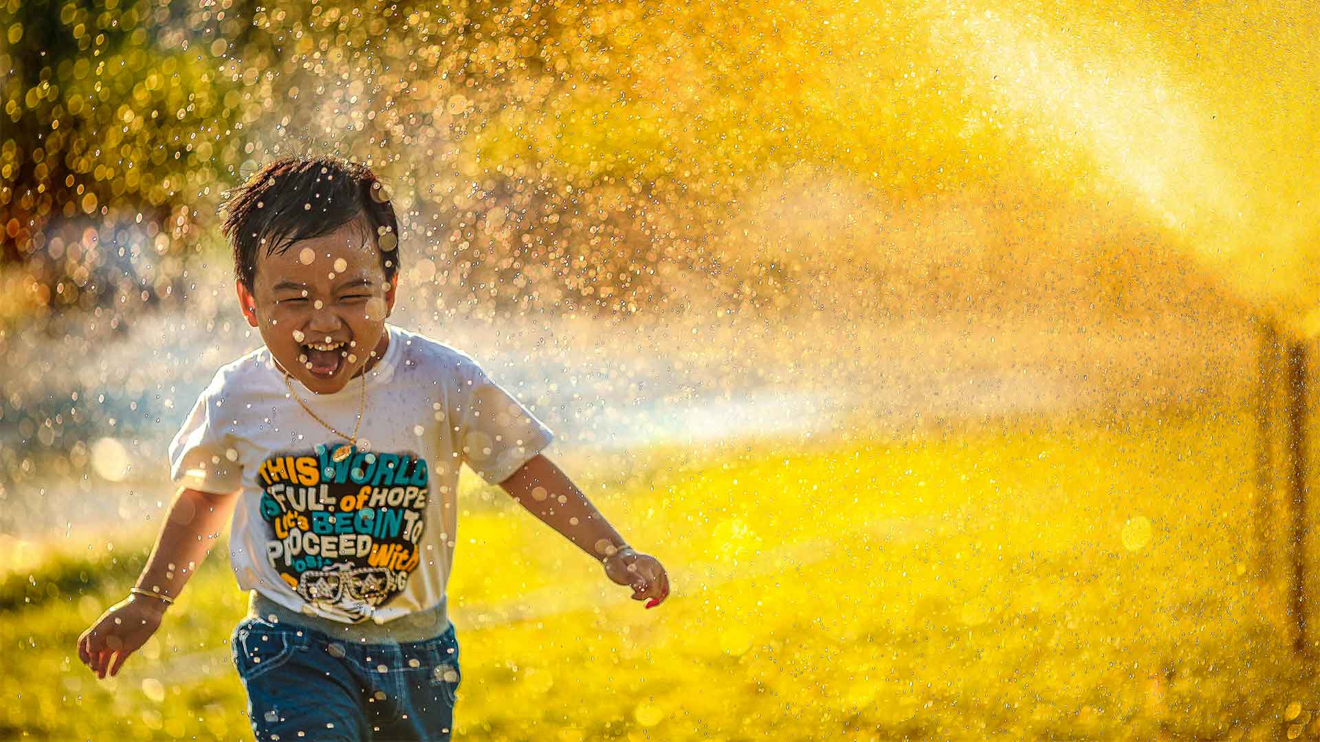 Enfant joyeux qui court sous un tuyau d'arrosage