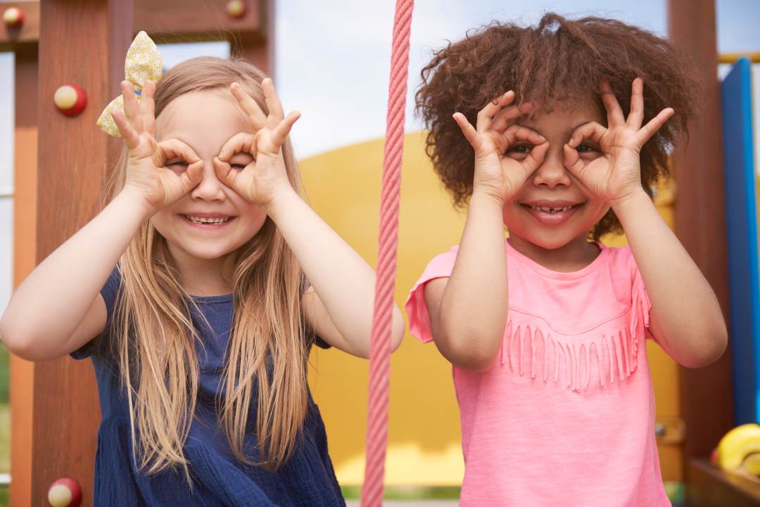 deux enfants de 3, 4 ans jouent à nous voir avec des jumelles faites de leurs doigts