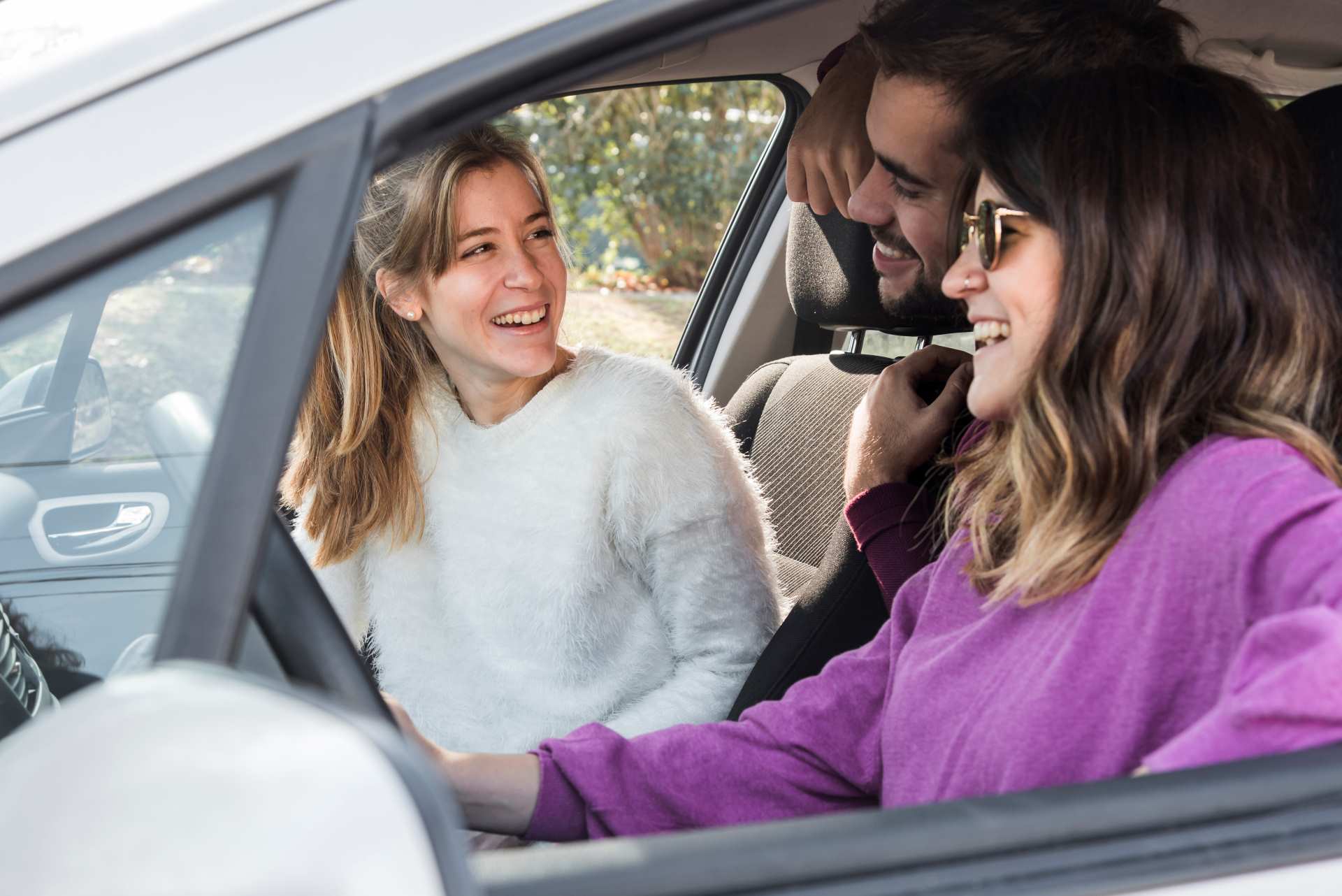 3 amis en voiture souriant covoiturent