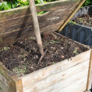 Vue sur du compost dans un composteur avec un fourche à l'intérieur